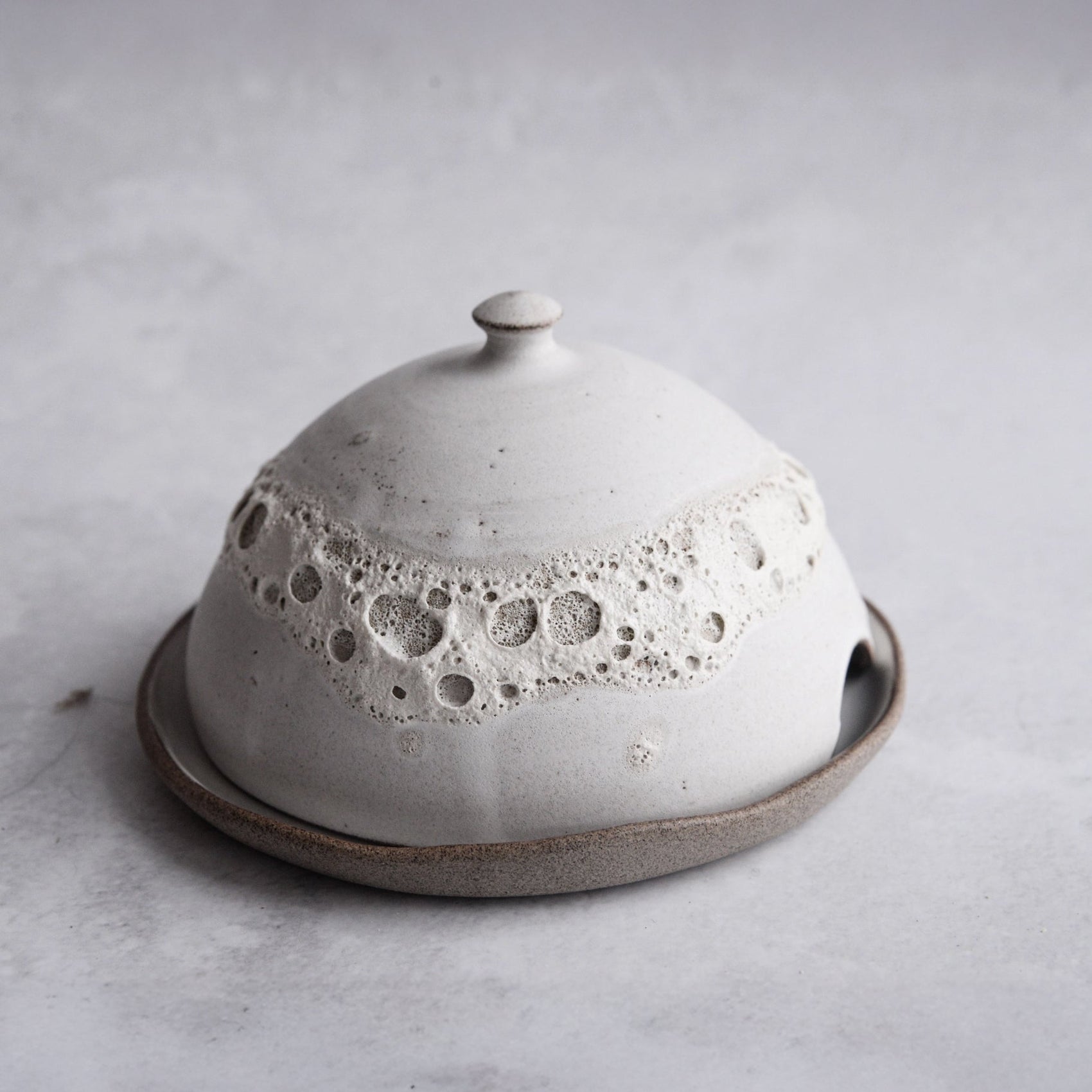 Ceramic butter dish with textured surface on a light gray background