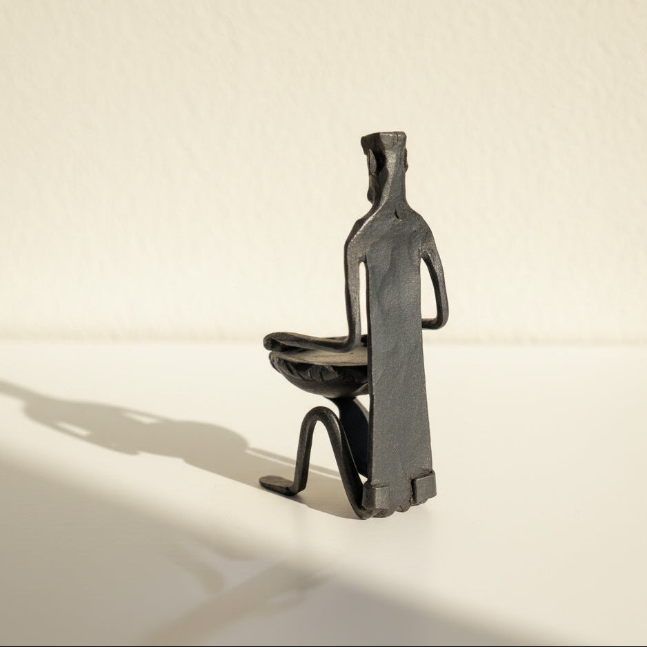 Abstract sculpture of a person on a pedestal against a beige background