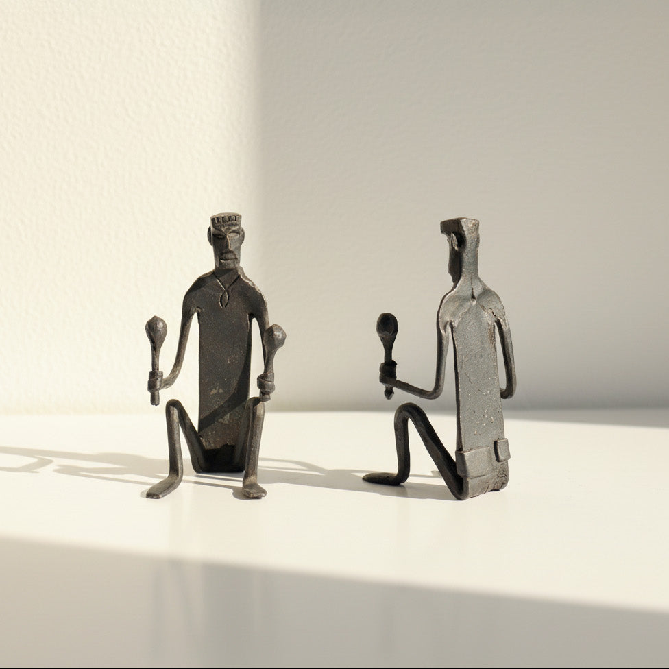 Two metallic figurines on a light surface with a neutral background