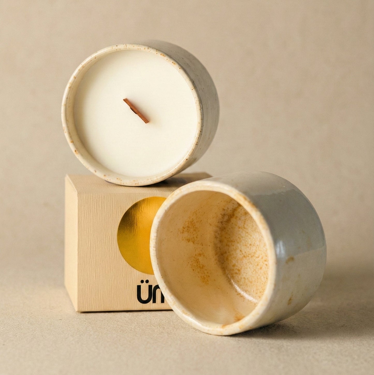 Two wooden candle holders with a candle inside on a beige background