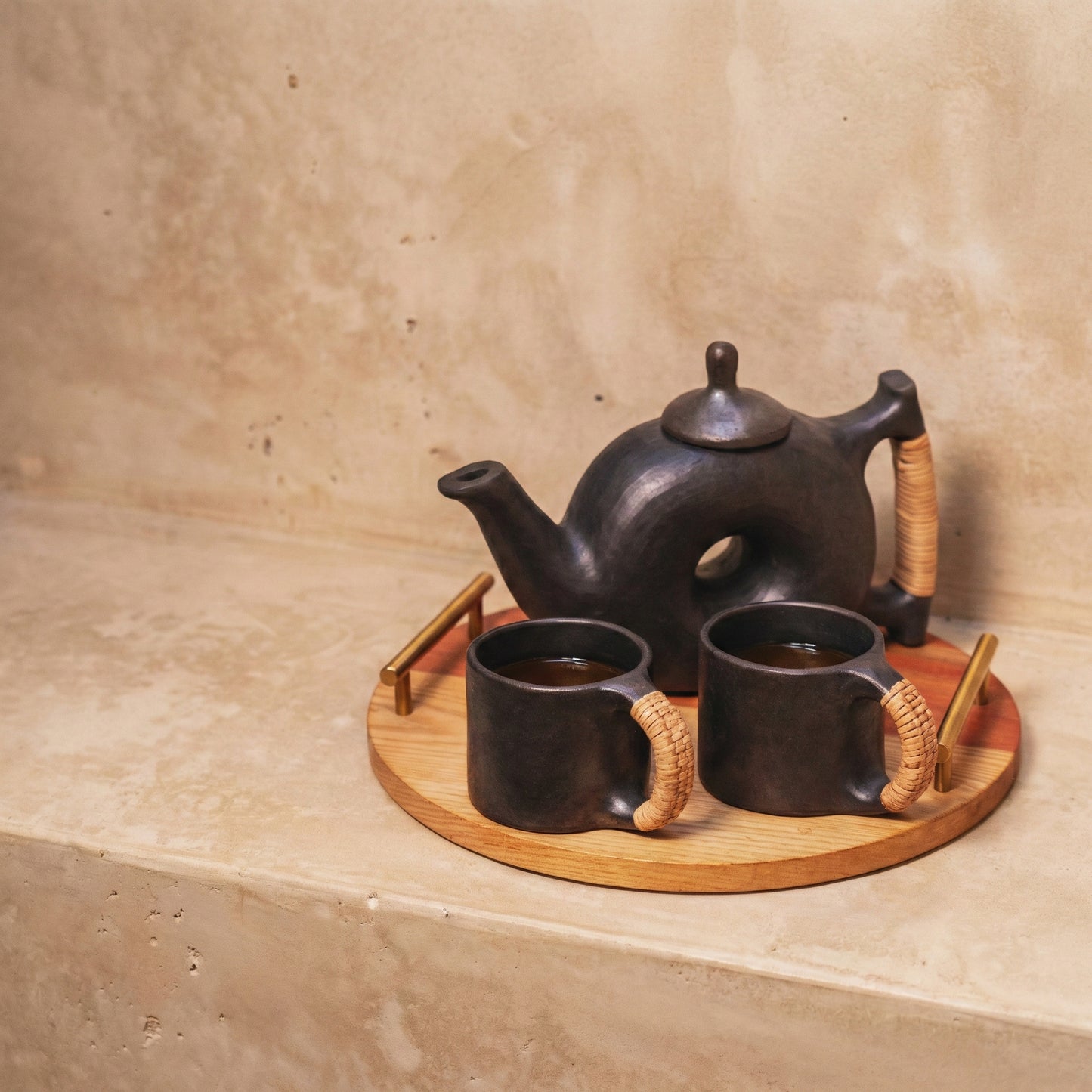 Close-up of The Chakra Teapot showing the central aperture and matte black finish polished with sahi tree leaves