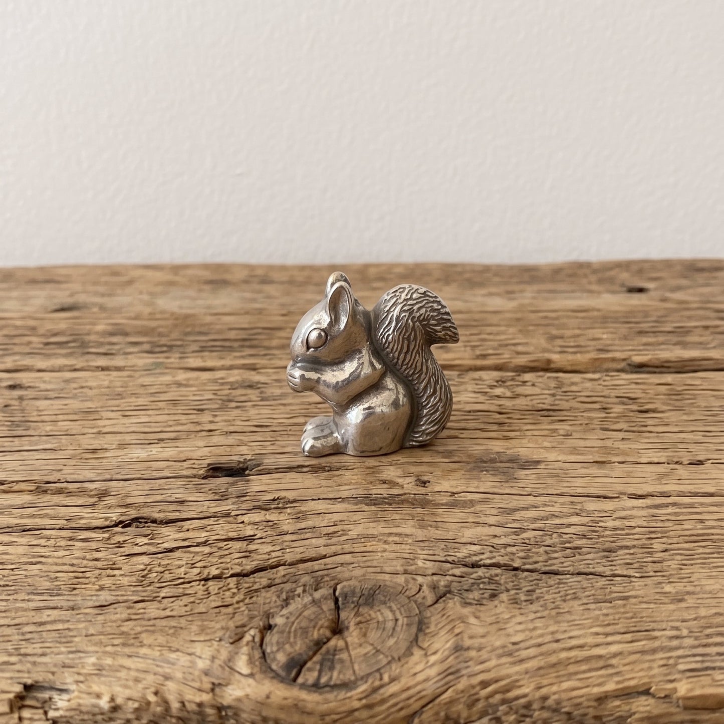 squirrel netsuke holding a nut, standing on a cut log