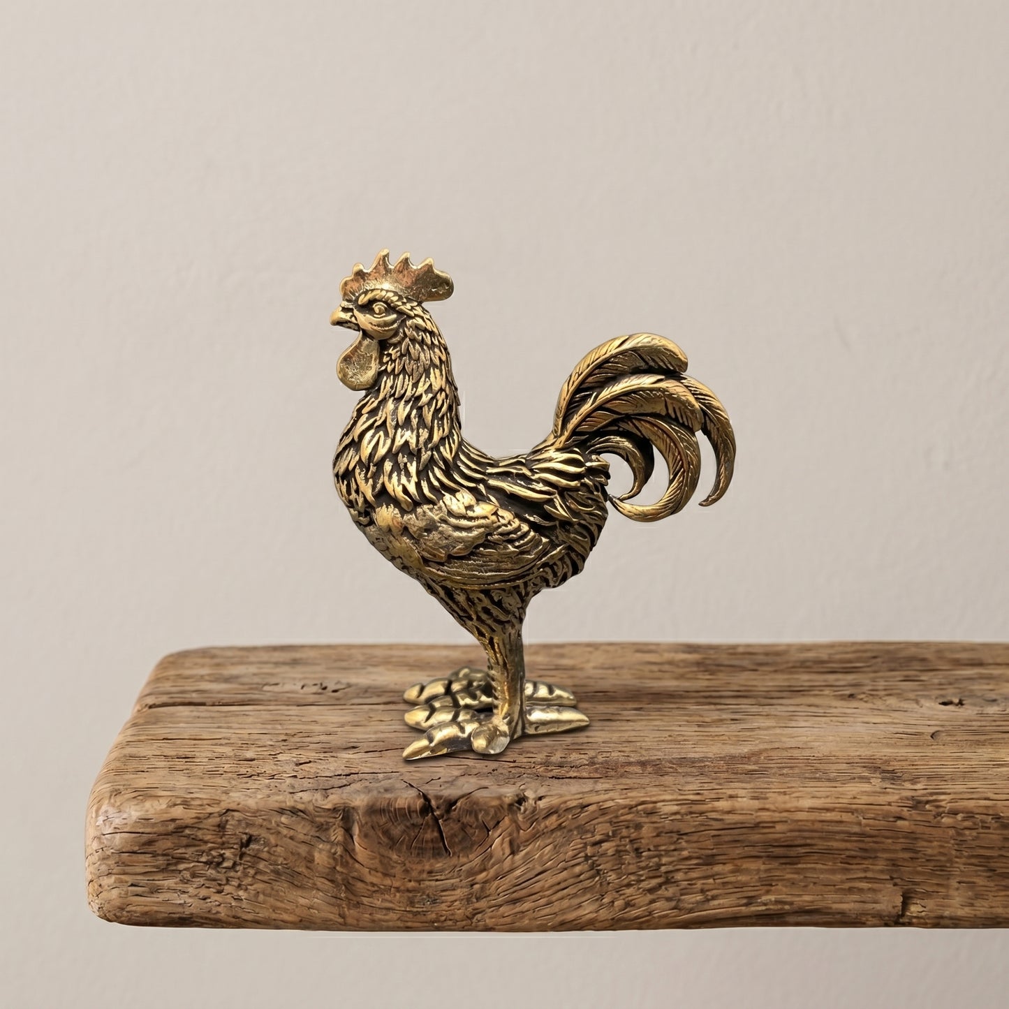 Side view of The Herald brass rooster showing the detailed hackle, saddle, and sweeping tail feathers