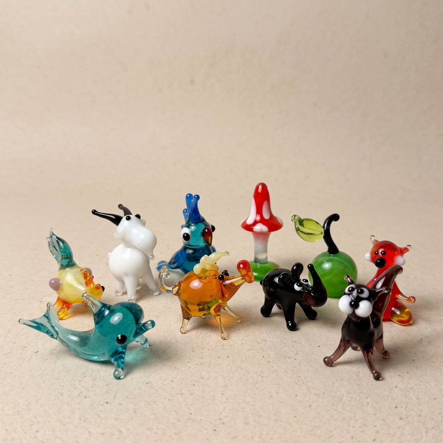 The Enchanted set of 10 miniature lampworked glass figurines including teal whale, white goat, blue parrot, red mushroom, green cat, black puppy, amber horse, and red fox, by Glass by Iness