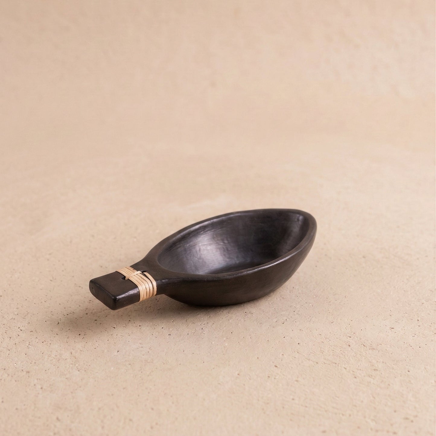 Patra serving bowl in Longpi black pottery showing woven handle detail and metallic black serpentinite stone finish