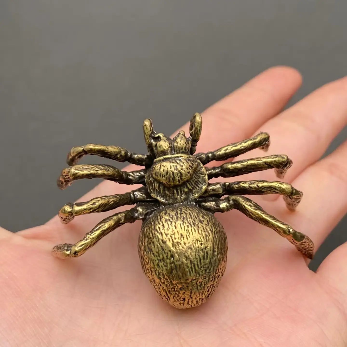 The Silent Architect miniature brass spider figurine on a neutral surface, showing detailed legs and aged golden patina, from the WILLAGE Tiny Objects collection
