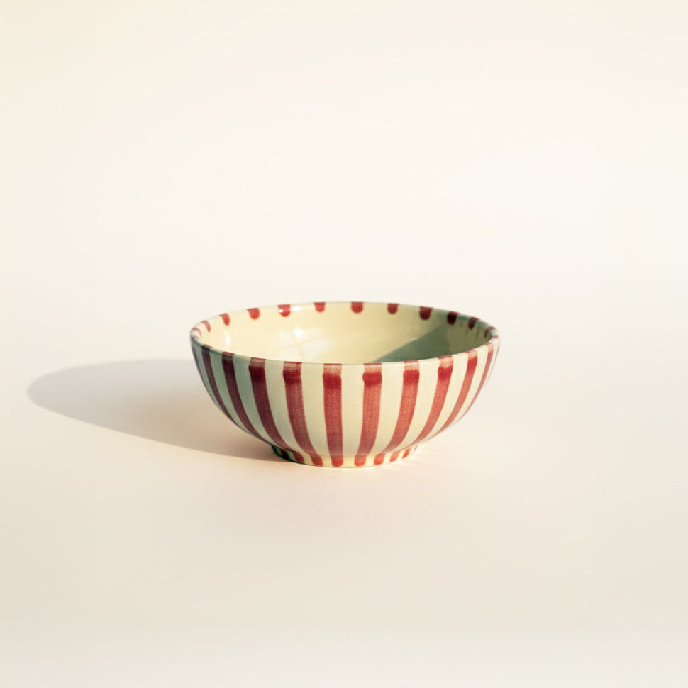 Ceramic bowl with red and white striped pattern on a beige background