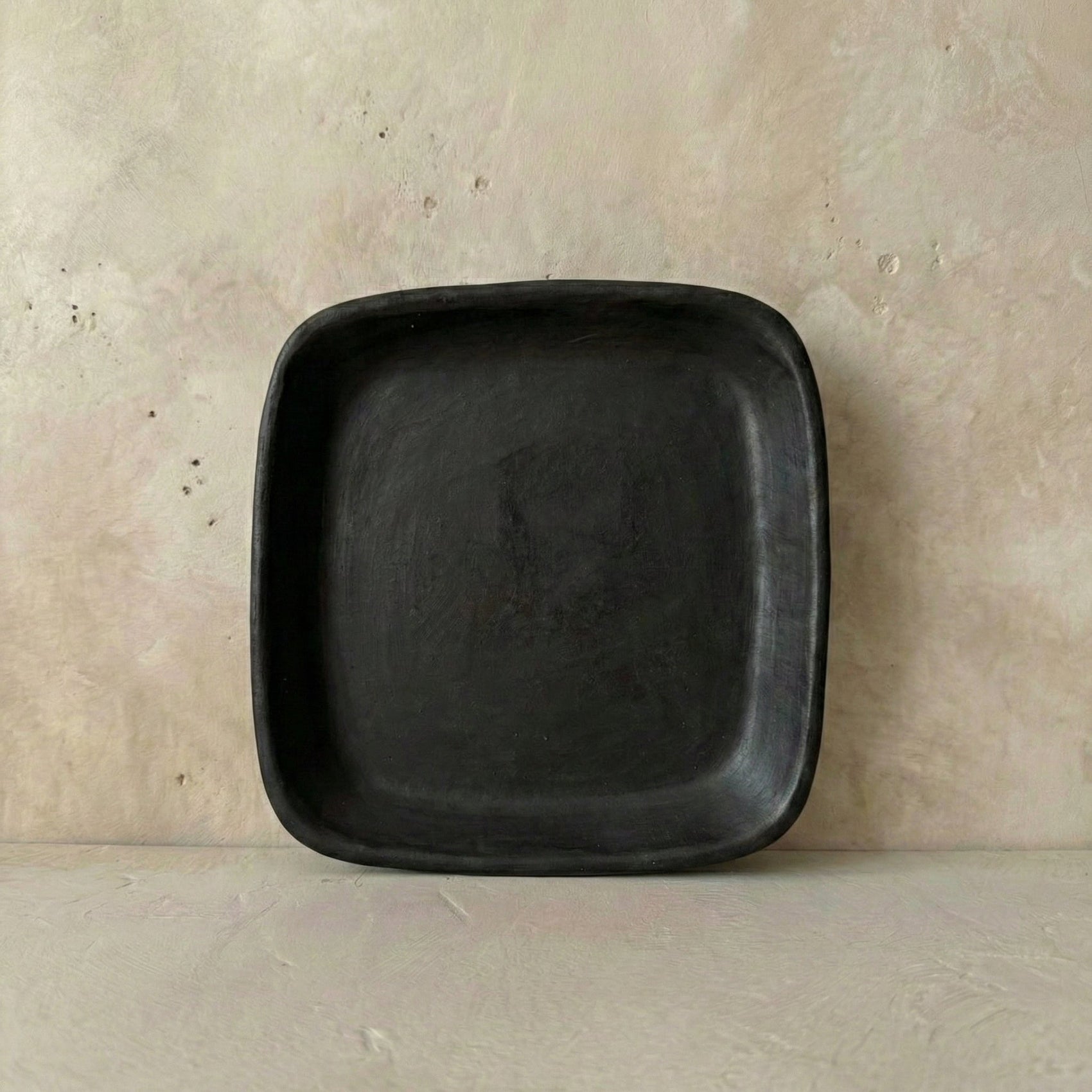 Black square plate on a beige surface