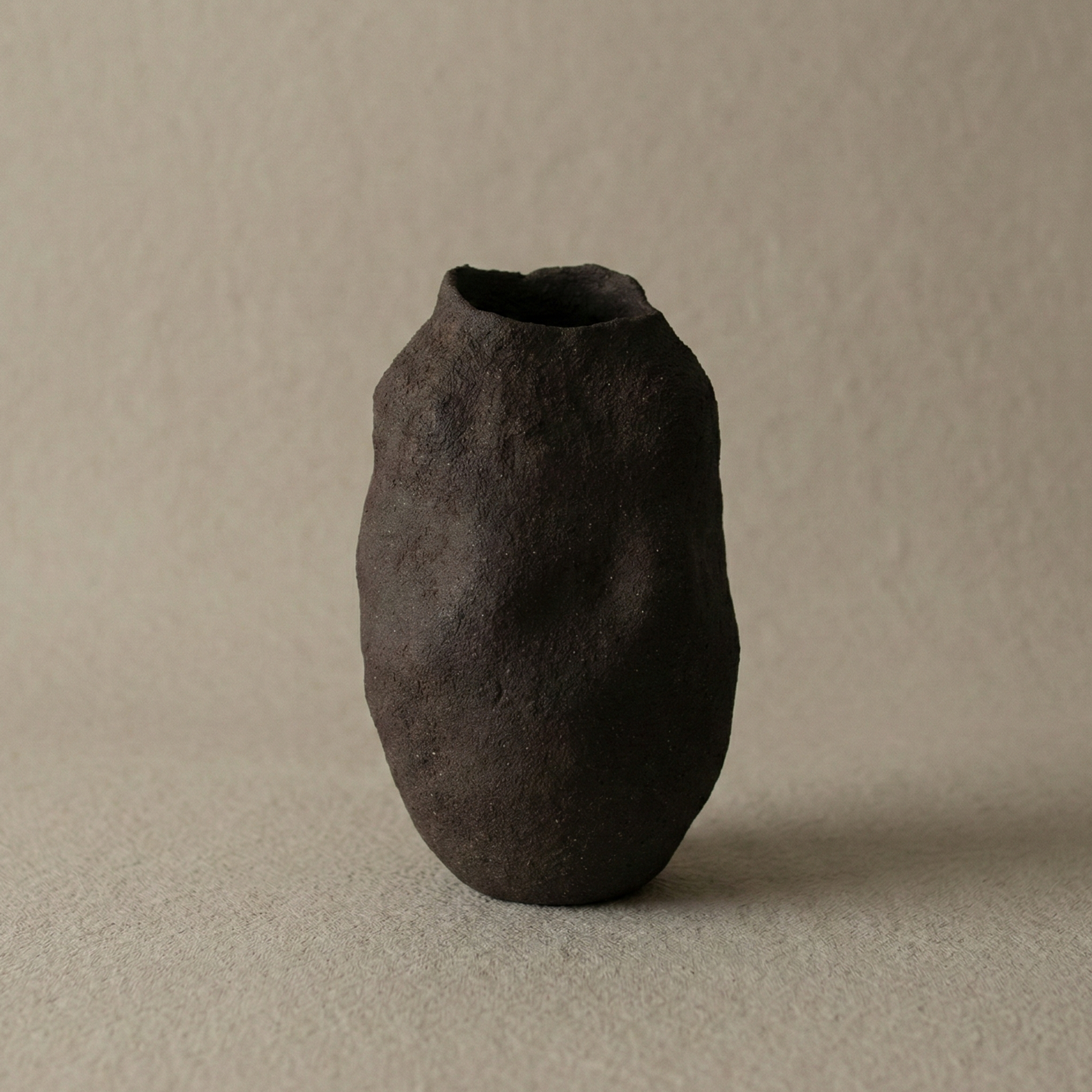 Dark brown ceramic vase on a beige background