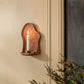 Wall-mounted candle holder with a candle on a beige wall.