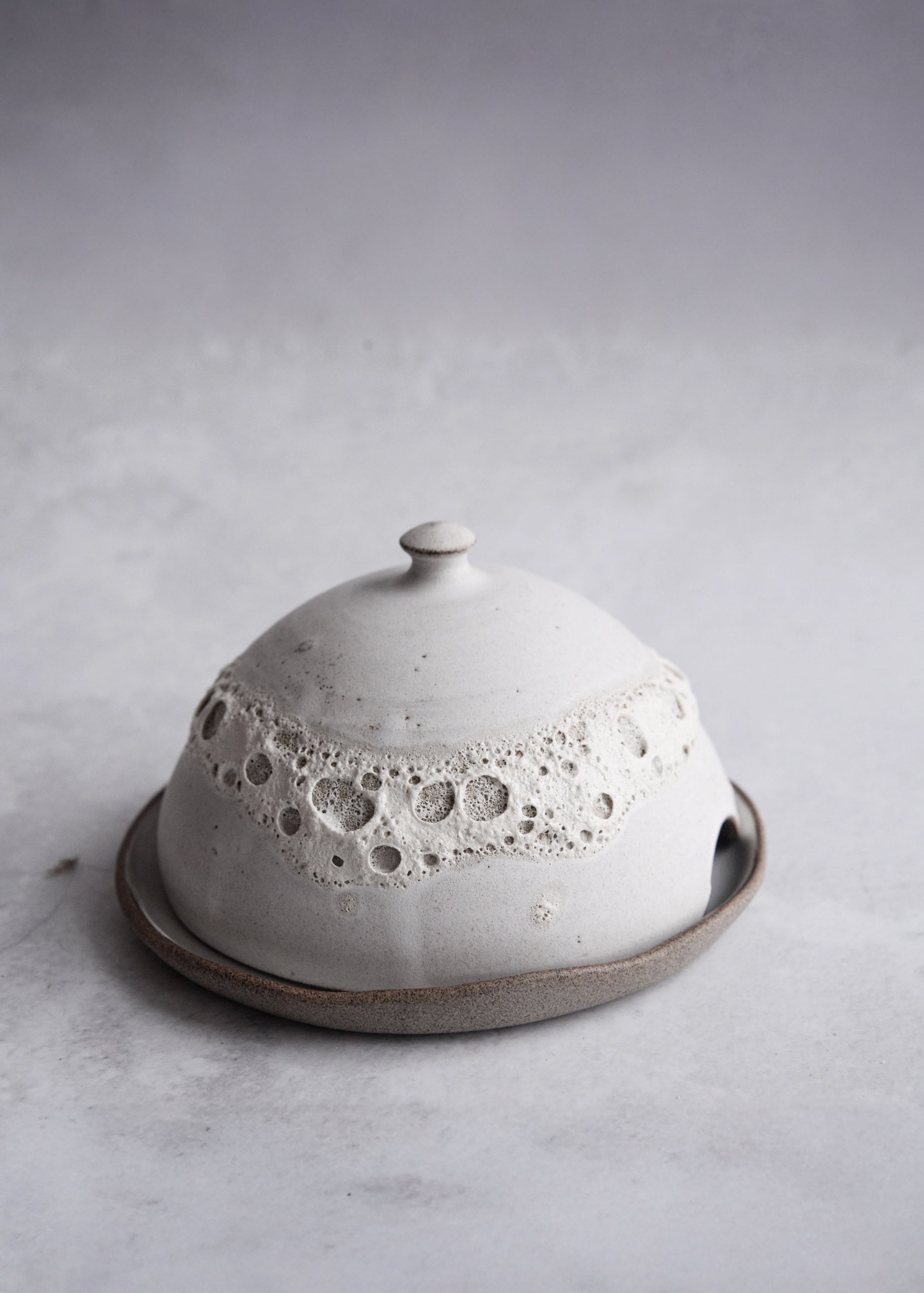 Ceramic butter dish with textured surface on a light gray background