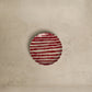 Round red and white striped object on a beige background