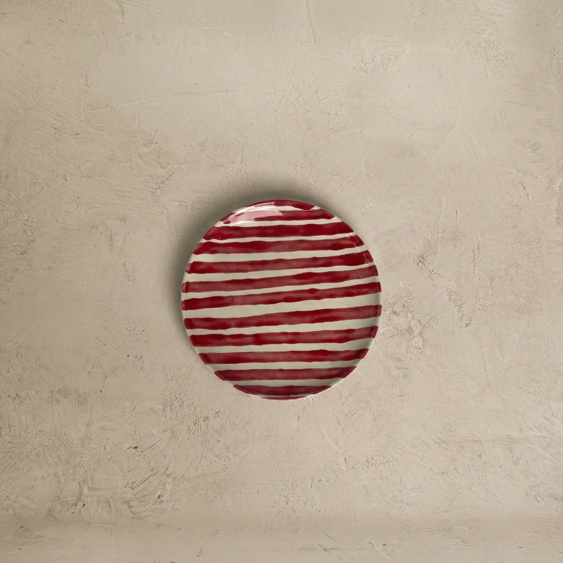 Round red and white striped object on a beige background