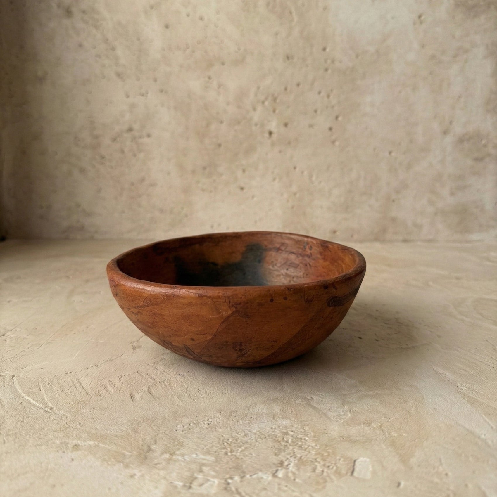 Clay bowl on a textured beige surface with a neutral background