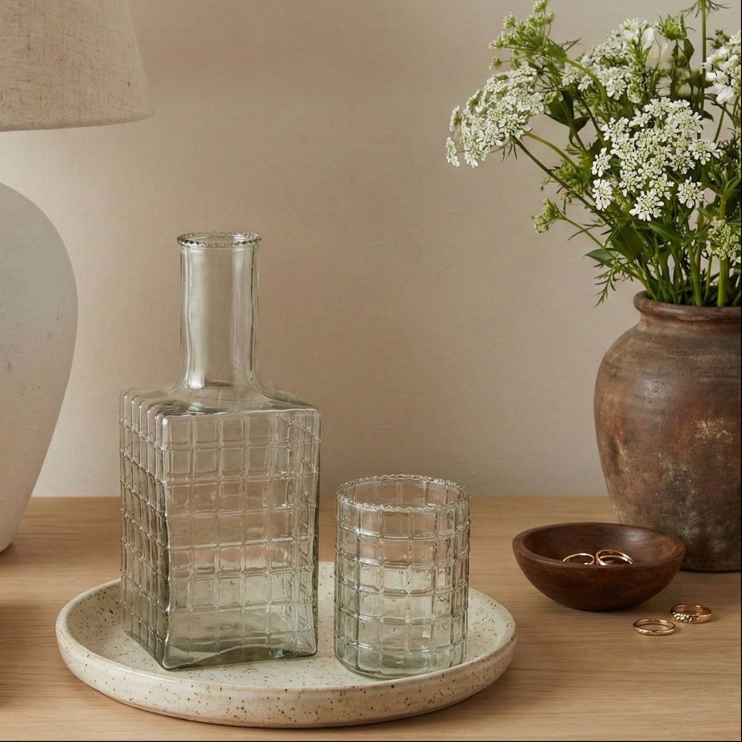 Decorative items on a wooden surface including a glass vase, a lamp, and a potted plant.