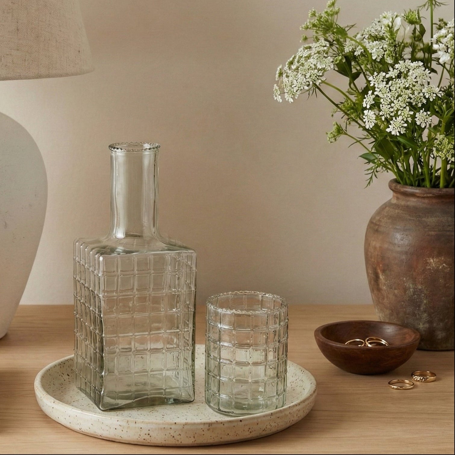 Decorative items on a wooden surface including a glass vase, a lamp, and a potted plant.