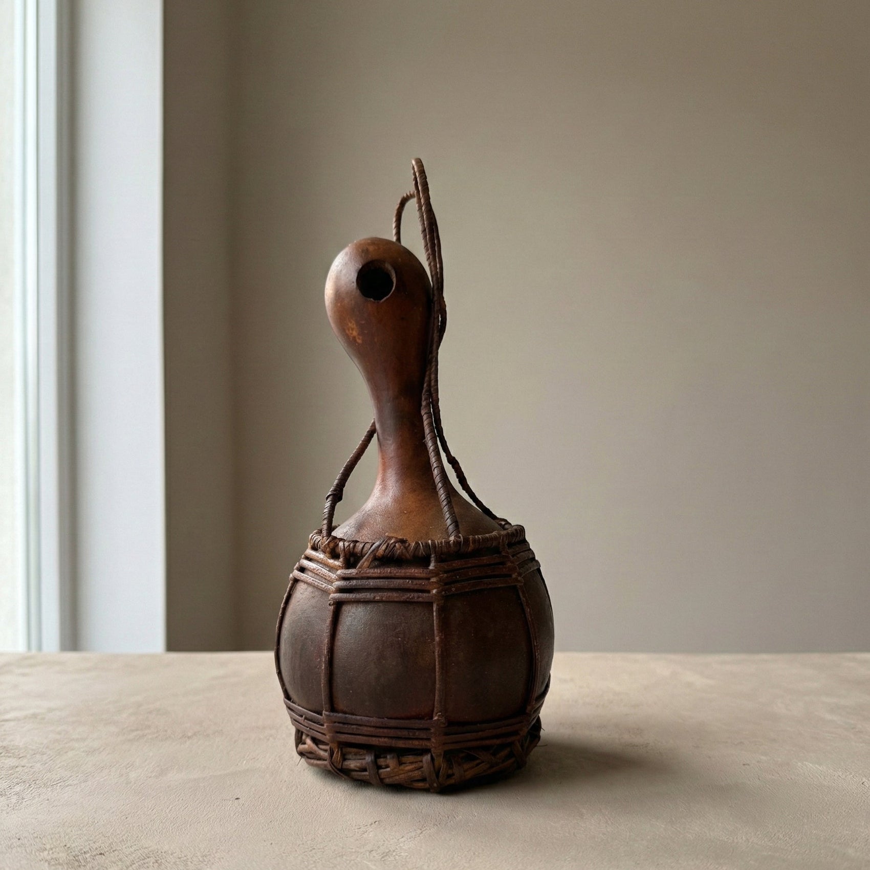 Brown gourd with a handle on a beige surface