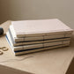 Stack of notebooks with a spool of thread and scissors on a wooden surface