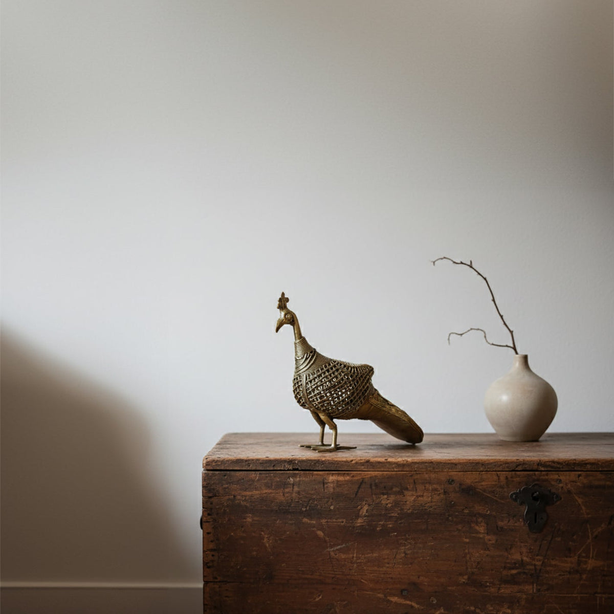 Decorative bird sculpture and vase on a wooden surface with a plain background