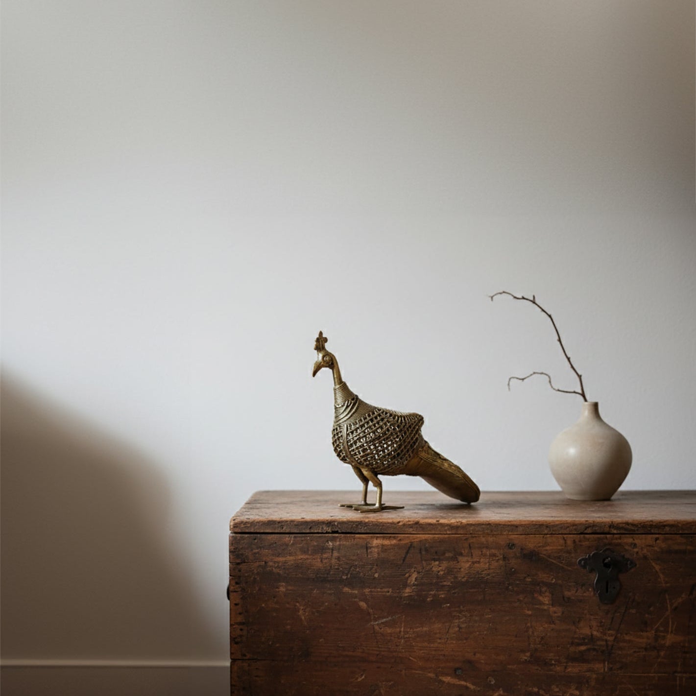Decorative bird sculpture and vase on a wooden surface with a plain background