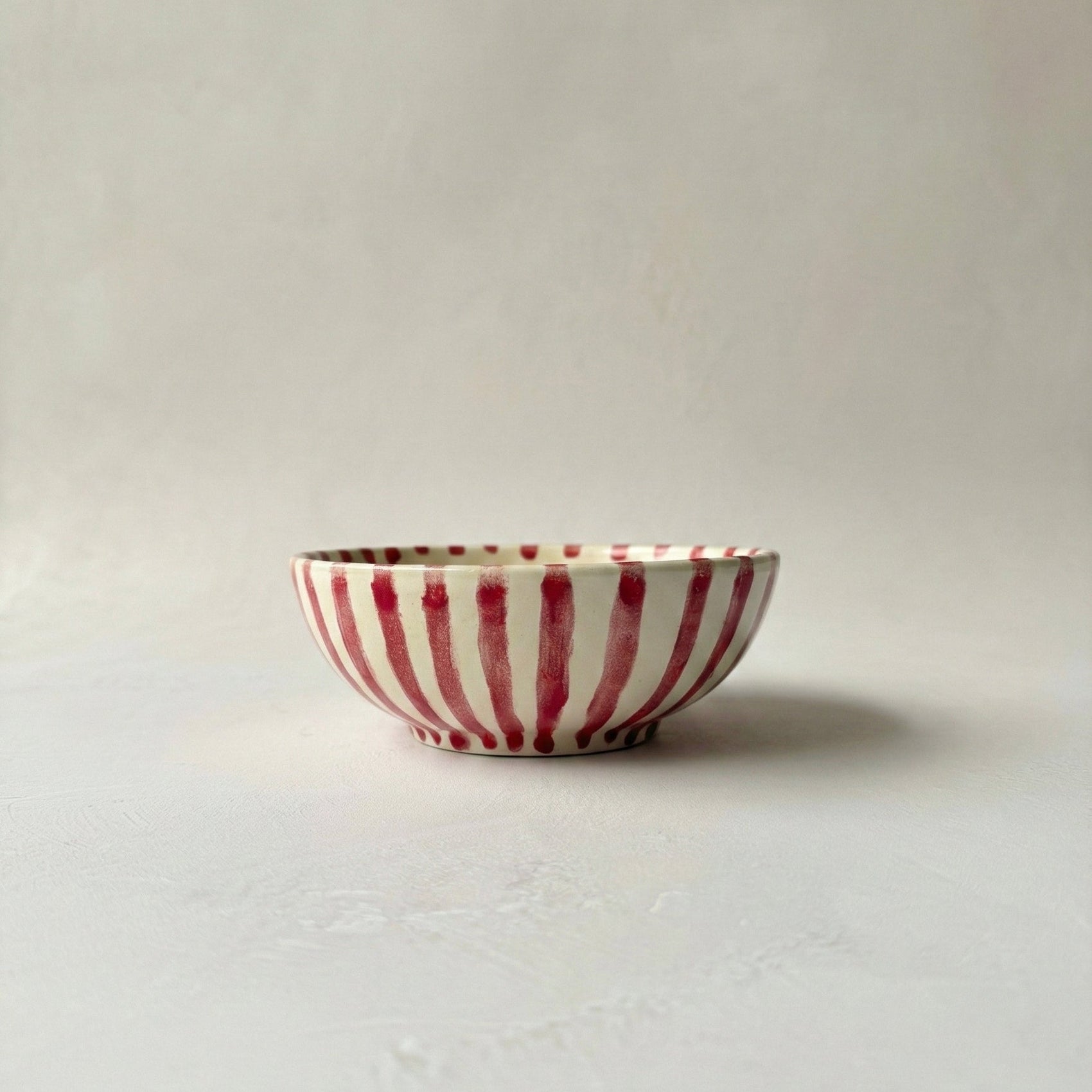 Red and white striped ceramic bowl on a light gray background
