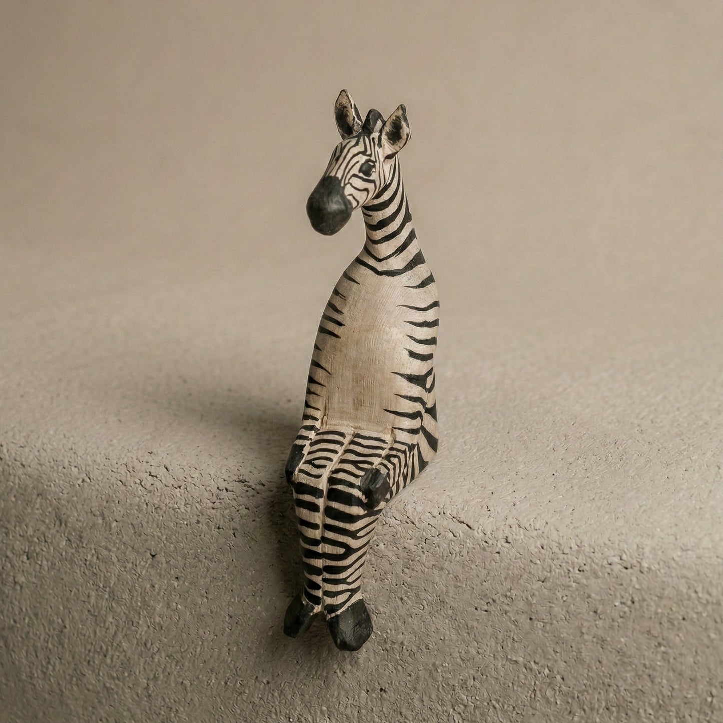 Zebra figurine on a textured surface with a neutral background