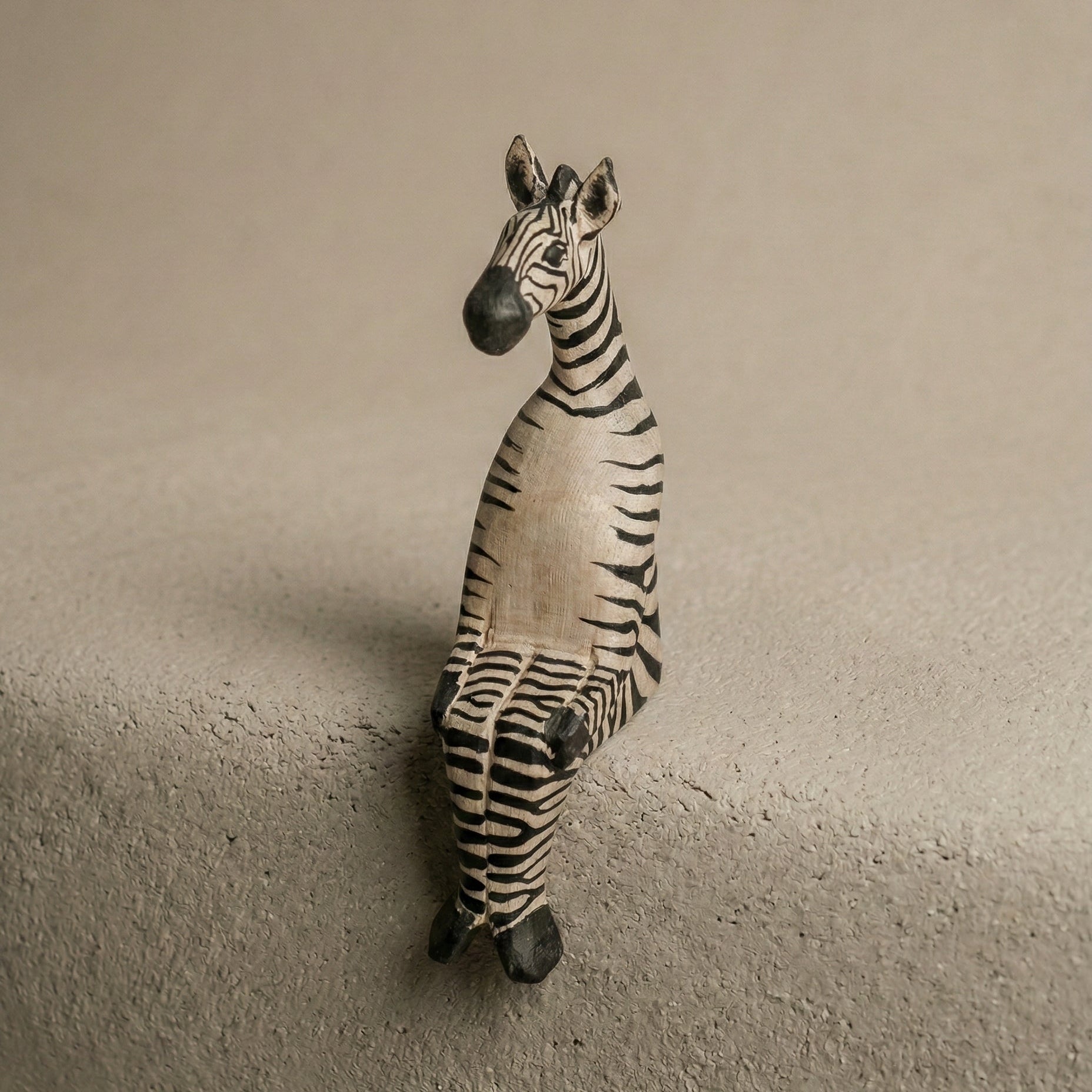 Zebra figurine on a textured surface with a neutral background
