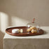The Acacia Provision Board and glass cloche showing hand-carved acacia wood base with warm grain variations and mouth-blown glass dome, handcrafted in India, from WILLAGE
