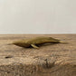 The Ancient Navigator miniature solid brass whale figurine with aged patina on natural stone surface
