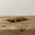 The Ancient Navigator miniature solid brass whale figurine with aged patina on natural stone surface
