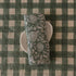 Block-printed European linen napkin in Rio Green botanical pattern folded on a white plate, showing peony and fern print detail, from WILLAGE
