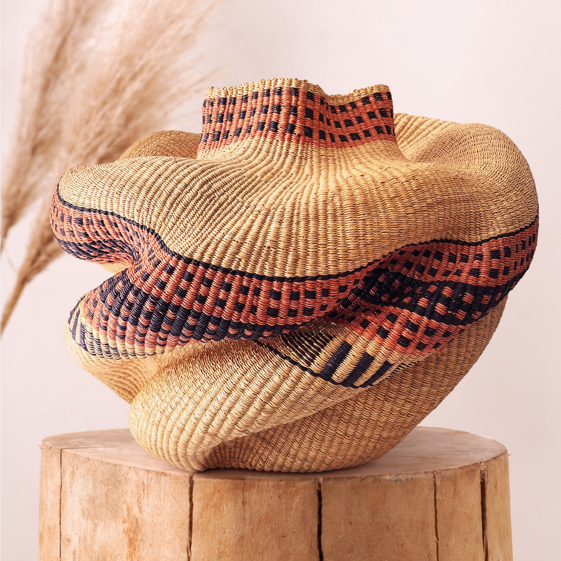 Bolgawoven elephant grass basket shown from alternate angle, showing organic woven form and natural dye pattern
