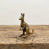 The Boundless Adventurer miniature brass kangaroo standing upright on a wooden surface, with warm aged patina, from the WILLAGE Tiny Objects collection
