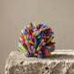 Side view of the rainbow felt hedgehog showing its full spread of multicolored organic wool spines