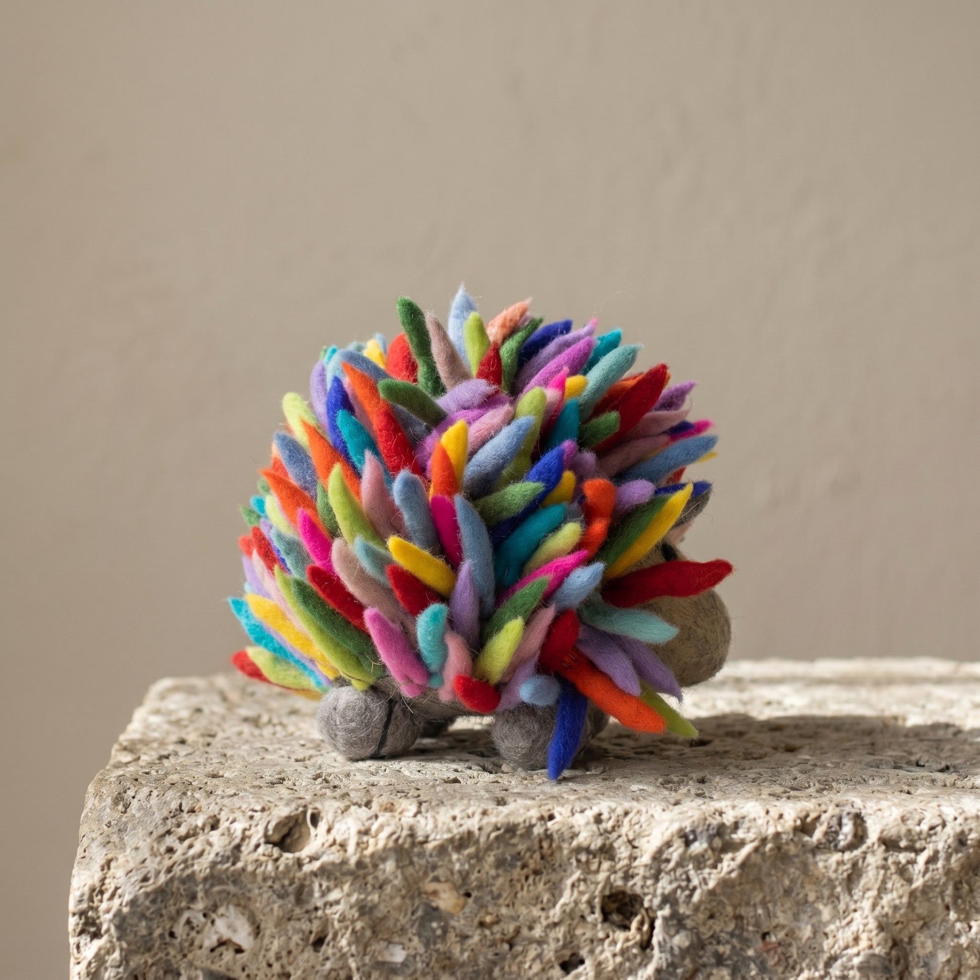 Side view of the rainbow felt hedgehog showing its full spread of multicolored organic wool spines
