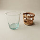 The Cỏ Tumbler close-up showing hand-woven seagrass sleeve texture and clear recycled glass underneath