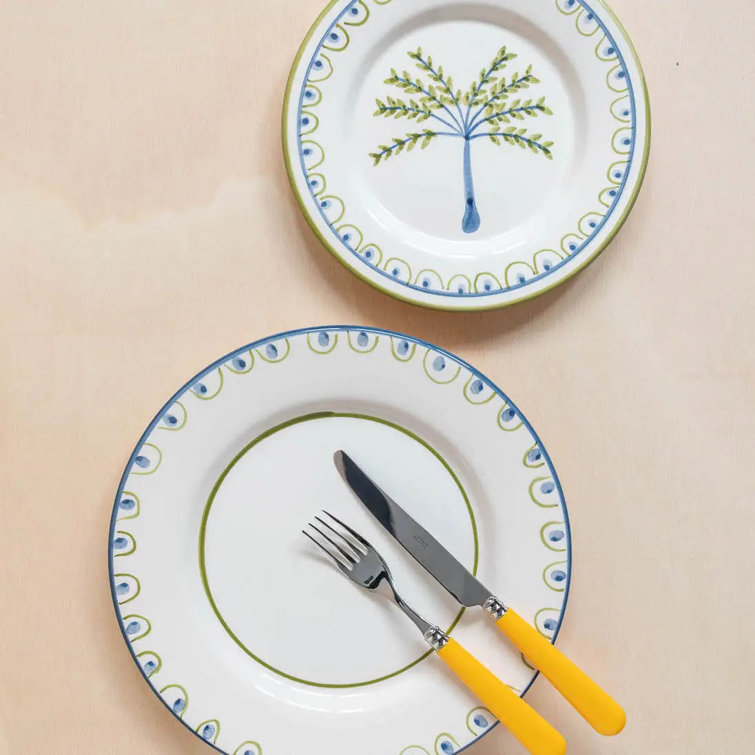 Hand-painted Portuguese dinner plate styled on a wooden table with candles and citrus, from Raquel Souza studio