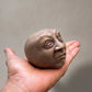 Palm-sized concrete sculpture of a head with eyes closed and mouth open as if Palm-sized concrete sculpture of a head with eyes closed and mouth open as if singing, matte stone finish, , matte stone finish 