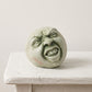 Palm-sized concrete sculpture of a head with eyes closed and mouth open as if singing, matte stone finish, on a white background