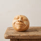 Palm-sized concrete sculpture of a head with eyes closed and mouth open as if singing, matte stone finish, on a white background _Lemon Yellow