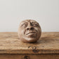 Palm-sized concrete sculpture of a head with eyes closed and mouth open as if singing, matte stone finish, on a white background- Thinking 