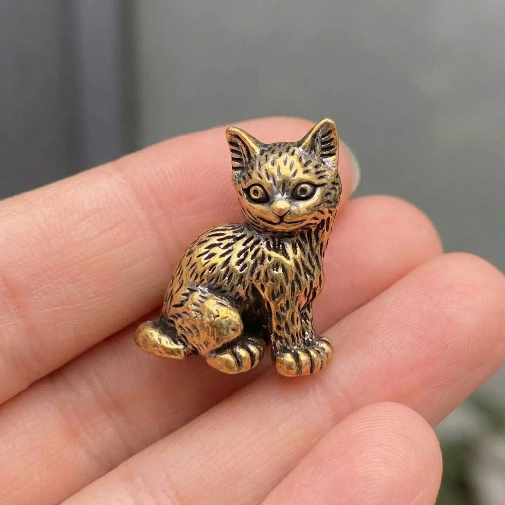 Close-up of The Curious One brass kitten showing hand-cast detail and small scale