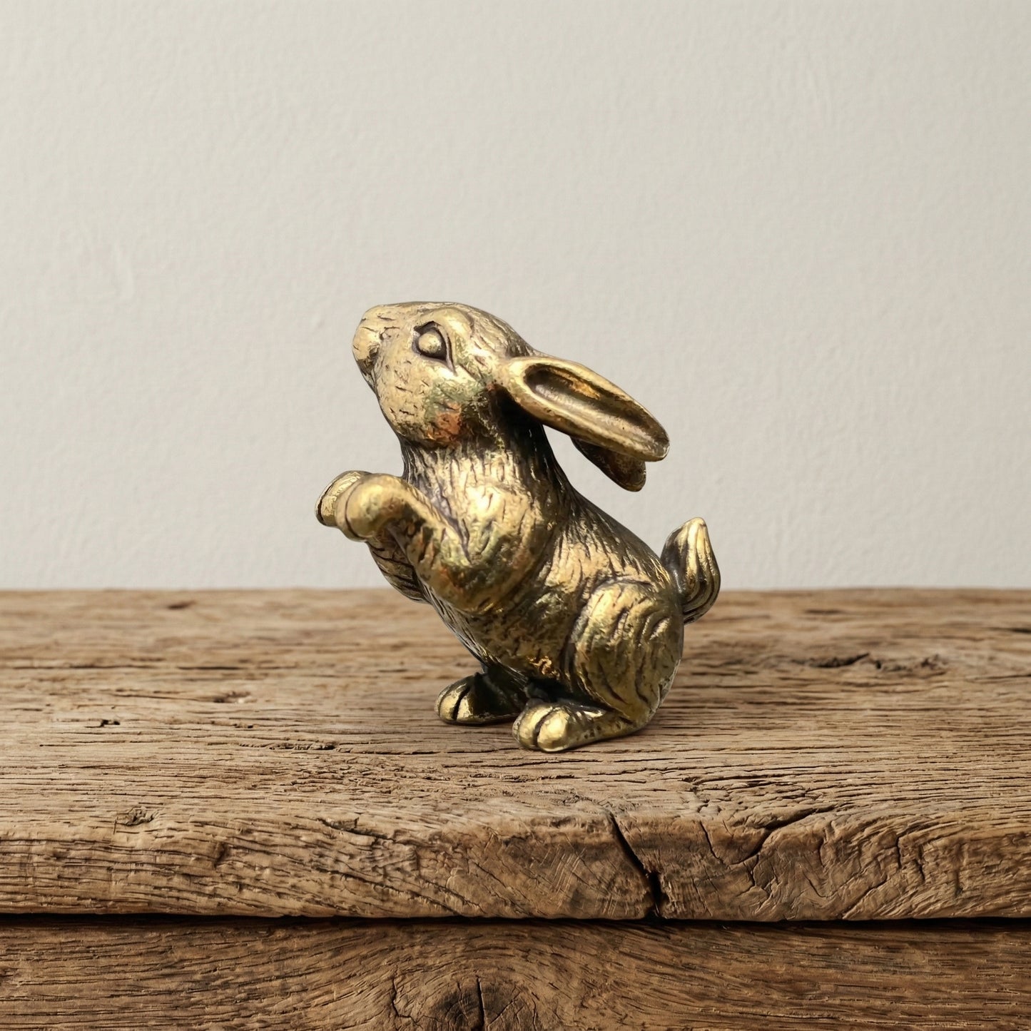 The Curious Sentinel miniature brass standing bunny on a wooden surface, upright on hind legs with ears raised and warm aged patina, from the WILLAGE Tiny Objects collection