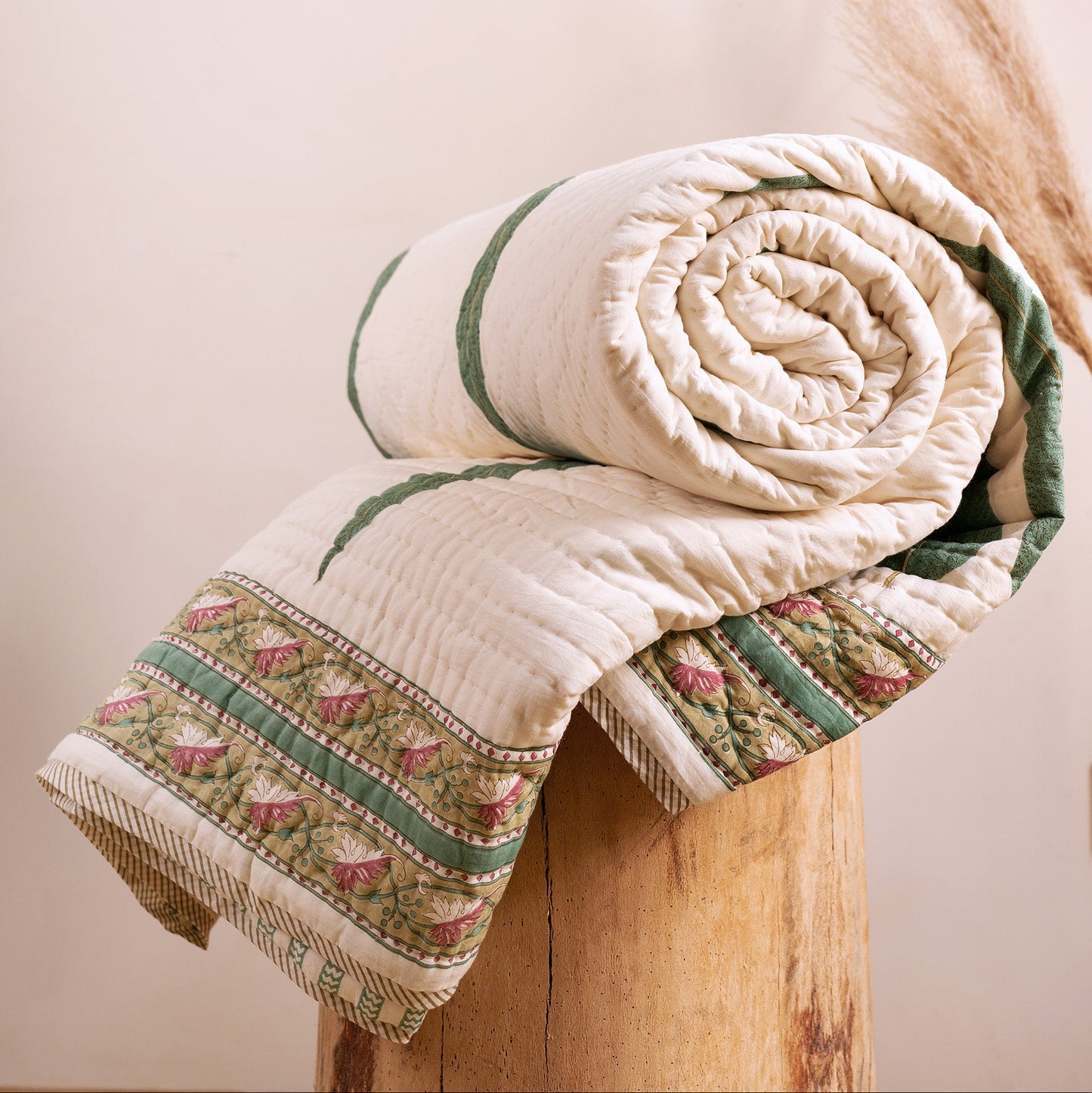 Cypress leaf hand block-printed quilt from Jaipur India, rolled on wooden stool, showing green and cream cotton voile, from WILLAGE