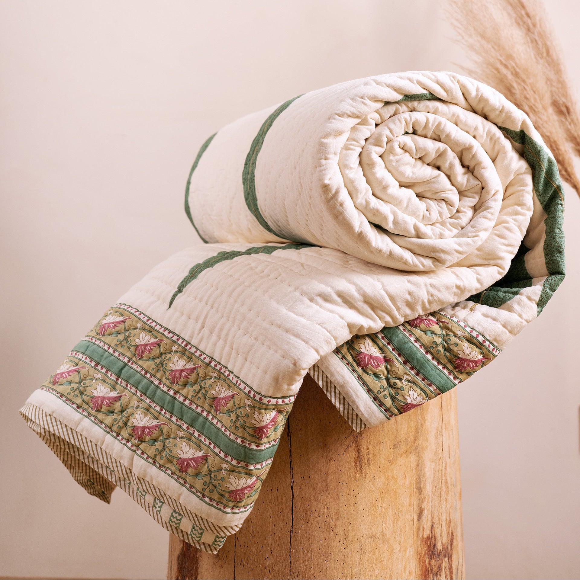 Cypress leaf hand block-printed quilt from Jaipur India, rolled on wooden stool, showing green and cream cotton voile, from WILLAGE