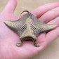 The Drifter brass manta ray held in a hand to show its size, about 3.3 inches across