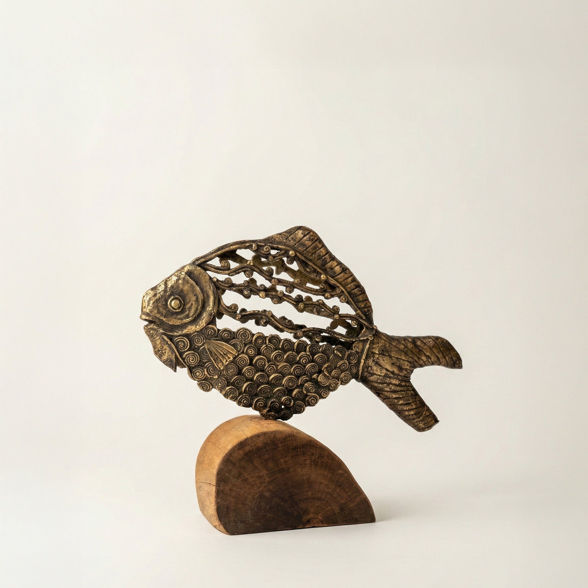 Side view of The Eternal Current Dhokra fish sculpture showing spiraling surface detail and wooden base