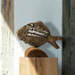 The Eternal Current Dhokra lost-wax cast metal fish sculpture by Rahul Dey displayed on a wooden pedestal in warm afternoon light, showing spiral scale detail and cast latticework, handcrafted in Kolkata India, from WILLAGE