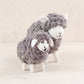 Two wooly hand-felted sheep in natural grey wool with cream faces and legs, large and small, on a white background