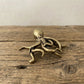 The Fluid Intellect miniature brass octopus showing detailed tentacles and golden patina against a neutral background